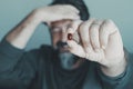 Close up of man holding red pill against migraine headache. Person in background holding and touching his front with pain. Concept Royalty Free Stock Photo