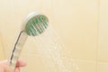 Close up of man holding shower head in the bathroom cabin.A stream of water pours from the shower Royalty Free Stock Photo