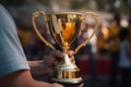 A close-up of A man holding up a gold trophy cup as a winner in a competition AI generated Royalty Free Stock Photo