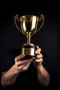 A close-up of A man holding up a gold trophy cup as a winner in a competition AI generated Royalty Free Stock Photo