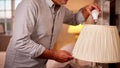 Close Up Of Man At Home Changing Bulb In Lamp To Energy Saving LED Unit