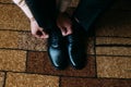 Close up of man leg and hands tying stylish black shoe laces standing on carpet with rectangular ornament Royalty Free Stock Photo