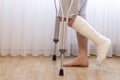 Close-up of man leg in plaster cast using crutches while walking.