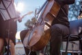 Male violoncellist playing cello in orchestra on the street