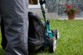 Close-up of a man in overalls with a lawn mower cutting grass in a modern garden Royalty Free Stock Photo