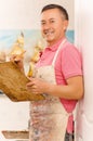 Close up of a man painter with color palette and paint brush in hand, in a studio blurred background