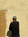 Close-up a man paints his house beige with a spray gun. worker spraying paint over timber wood. Construction worker with spray gun Royalty Free Stock Photo