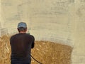 Close-up a man paints his house beige with a spray gun. worker spraying paint over timber wood. Construction worker with spray gun Royalty Free Stock Photo