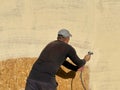 Close-up a man paints his house beige with a spray gun. worker spraying paint over timber wood. Construction worker with spray gun Royalty Free Stock Photo