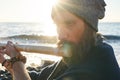 Close up man playing on bansuri traditional Indian instrument at sunrise seaside.