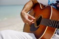 Close-up of a man playing a classical guitar while sitting on the beach in summer. Lifestyle, rest, relaxation Royalty Free Stock Photo