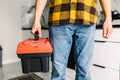 Close up young man plumber holding toolbox in the kitchen a prepare for work