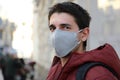 Close up of man in protective mask outdoors. Young man stands in street and looking at camera