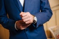 Close-up man puts on a gold watch with a leather belt, businessman is dressed in a stylish suit, a white shirt. Royalty Free Stock Photo