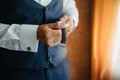 Close-up man puts on a gold watch with a leather belt, businessman is dressed in a stylish suit, a white shirt. Royalty Free Stock Photo