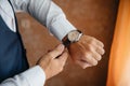 Close-up man puts on a gold watch with a leather belt, businessman is dressed in a stylish suit, a white shirt. Royalty Free Stock Photo