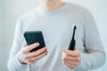 Close up man puts settings of his electronic toothbrush with mobile phone app. Wireless connecting sonic toothbrush with