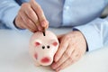 Close up of a man putting coin into piggy bank Royalty Free Stock Photo