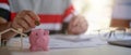 Close up of man putting coins in a piggy bank and calculating with calculator for saving money and financial home loan Royalty Free Stock Photo