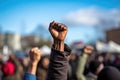 Close up of a man raised his fist in protest with crowd in the background, A raised fist of a protestor at a political