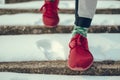 Mman in red sneakers walking down the snowy stairs