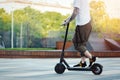 Close up of man riding black electric kick scooter at beautiful park landscape Royalty Free Stock Photo