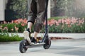 Close up of man riding black electric kick scooter at beautiful park landscape