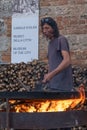 A close up of a man roasting chestnuts in a large pan with a fire underneath in an historic hilltop town in Tuscany