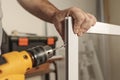 Close up of man`s hand holding electric boring machine. Making a hole in an aluminum profile of a mosquito net