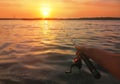 Close-up of a man`s hand holding a fishing rod near the river at sunset, panorama of the water and the coast Royalty Free Stock Photo