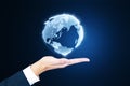 Close up of man's hand holding glowing globe hologram on blurry background. Digital earth and metaverse concept Royalty Free Stock Photo