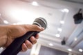 Close up of man`s hand holding microphone in conference hall or Royalty Free Stock Photo