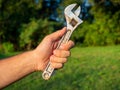 Close-up of a man`s hand holding an old adjustable wrench. Blurry green background. The concept of a tool for work Royalty Free Stock Photo