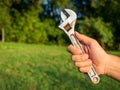 Close-up of a man`s hand holding an old adjustable wrench. Blurry green background. The concept of a tool for work. Copy space Royalty Free Stock Photo