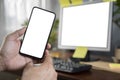 Close up with man`s hand holding smartphone in front of laptop, blank screen of smartphone and laptop Royalty Free Stock Photo