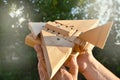 Close-up of a man`s hand holding a wooden toy HOMEMADE airplane against a background of trees, light and sunlight on a