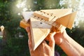 Close-up of a man`s hand holding a wooden toy HOMEMADE airplane against a background of trees, light and sunlight on a