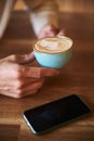 Close up of man& x27;s hand with latte art coffee cup in cafe, selective focus, food and drink concept Royalty Free Stock Photo