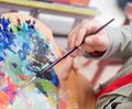 Close up of man`s hand mix paints with brush in palette and painting still life picture on canvas in artist studio Royalty Free Stock Photo