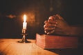 Close up man`s hand is praying in the Church with lit candle