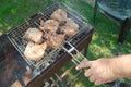 Close-up of a man`s hand preparing fried meat, outdoors, in summer, against the background of grass Royalty Free Stock Photo