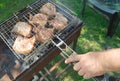 Close-up of a man`s hand preparing fried meat, outdoors, in summer, against the background of grass Royalty Free Stock Photo