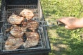 Close-up of a man`s hand preparing fried meat, outdoors, in summer, against the background of grass Royalty Free Stock Photo