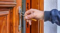 Close-up of a man's hand repairing an old wooden door with a metal key. Door repair worker. Royalty Free Stock Photo