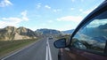 Close up of man`s hand on the steering wheel driving a car from side of car mirror mountain valley. Beautiful landscape Royalty Free Stock Photo