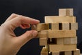 Close up of man`s hand take one block to a tower of wooden blocks, dark tone. Royalty Free Stock Photo