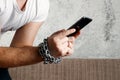 Close-up, the man`s hand is tied with a chain to the smartphone. The concept is dependent on technology, phone, social networks,