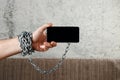 Close-up, the man`s hand is tied with a chain to the smartphone. The concept is dependent on technology, phone, social networks,