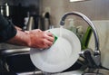 Man`s hand washing the dish under the kitchen sink faucet Royalty Free Stock Photo