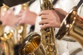 Close-up. A man`s hand in a white suit on a gold saxophone in a jazz band. Shallow depth of field.